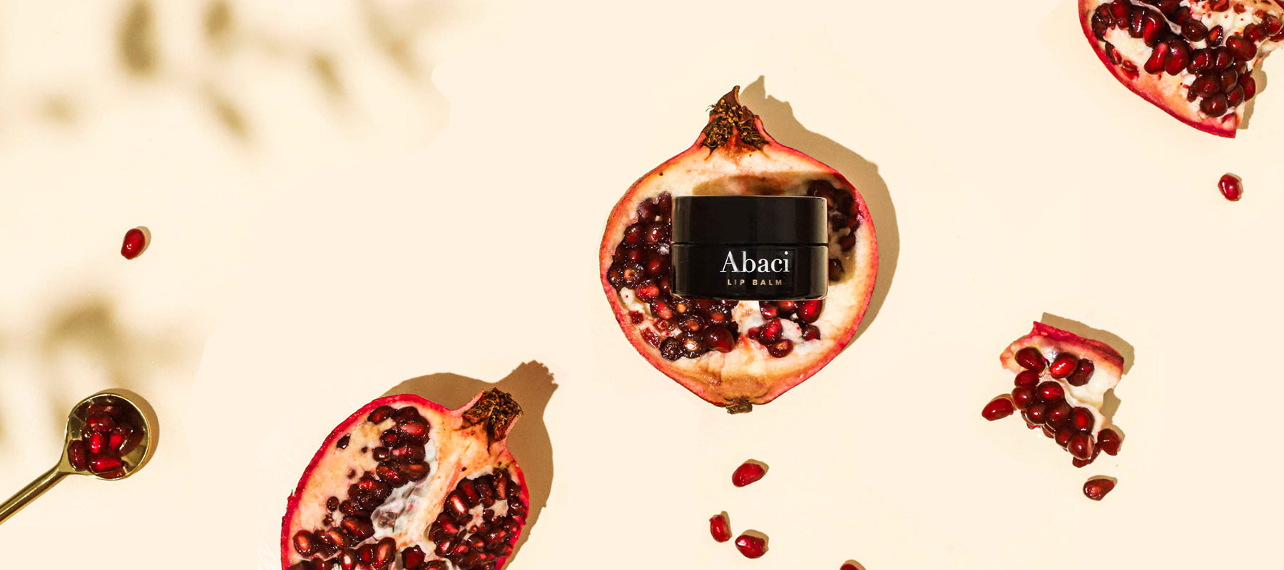 Abaci Organic Lip Balm featured among pomegranates and pomegranate seeds.